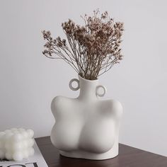 a white vase sitting on top of a wooden table