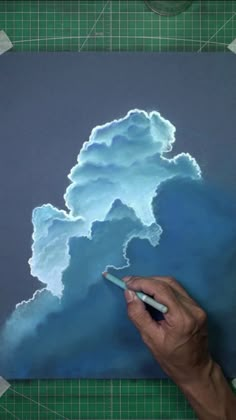 a person is drawing clouds on a piece of paper