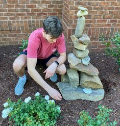 a young man is playing with rocks in the garden