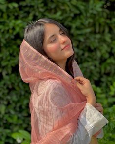 a woman in a pink shawl is posing for the camera with her eyes closed