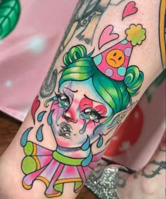 a woman's leg with tattoos on it and an image of a clown wearing a hat