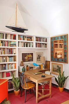 the room has many bookshelves and plants in it, as well as pictures on the wall