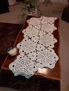 a table runner with crocheted doily on it sitting on a coffee table