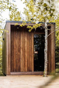 a small wooden outhouse sitting next to a tree