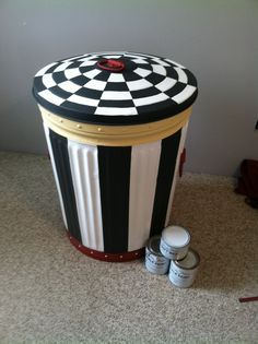 a black and white striped trash can sitting on the floor next to some paint cans