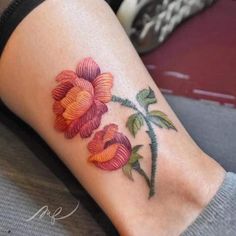 a close up of a person's foot with flowers tattooed on the lower leg