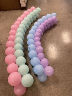 a long line of balloons in pastel pink, blue and white colors on the floor