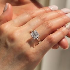 a woman's hand holding a ring with a diamond on it and the other hand