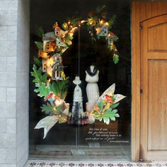 a store front window decorated with christmas wreaths and lights on the windows display mannequins