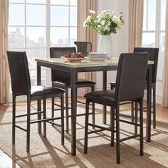 a kitchen table with four chairs and a bowl of fruit on it