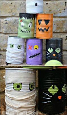 some tin cans with faces painted on them are stacked up in front of a brick wall