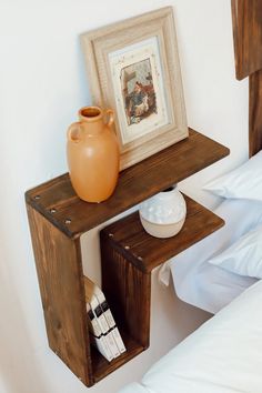 a brown vase sitting on top of a wooden shelf next to a white bedding