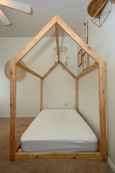 the bed frame is made out of wood and has a white sheet on top of it