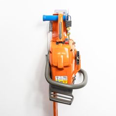 an orange and gray machine is hanging on the side of a white wall with a blue handle