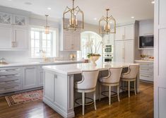 a large kitchen with white cabinets and wooden floors