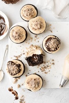 chocolate cupcakes with peanut butter frosting and chopped walnuts on a cutting board