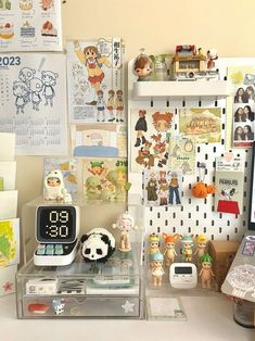 a desk with various items on it and pictures hanging up against the wall behind them