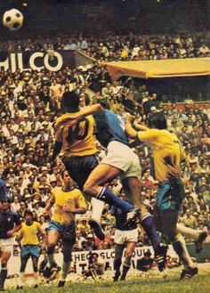 a group of men playing soccer against each other in front of an audience at a sporting event