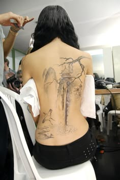 the back of a woman's body with tattoos on it