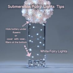 a clear vase filled with white flowers and lights on top of a gray background, labeled submersible fairy lights tips