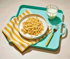 a bowl of macaroni and cheese next to a glass of milk on a tray