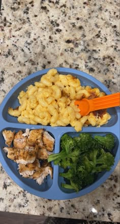 a blue plate topped with macaroni and broccoli on top of a counter