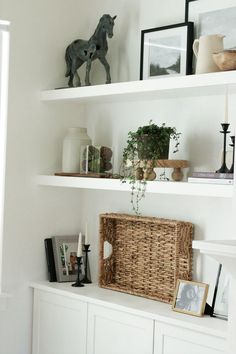 some white shelves with pictures and plants on them