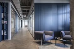 an empty room with chairs and bookshelves in front of blue walls that have glass doors