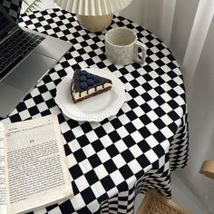 a laptop computer sitting on top of a table next to a slice of cake and cup