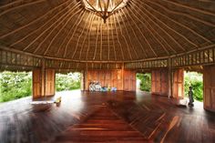 the inside of a hut with wooden floors and thatched roof, surrounded by greenery