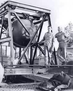 two men standing next to each other near a large object on a truck bed that is being unloaded