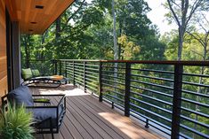 a wooden deck with chairs on it and trees in the backgroung area