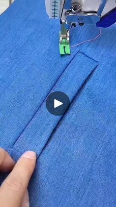 someone is sewing something on a blue piece of fabric with a green stitching needle