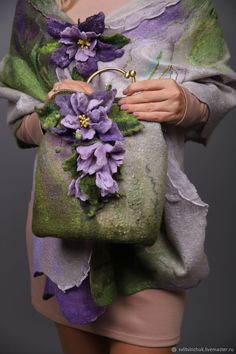 a woman holding a purse with purple flowers on it