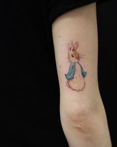 a small rabbit tattoo on the left inner forearm and wrist, with a blue scarf around it's neck