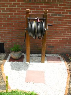 a garden hose dispenser in front of a brick wall