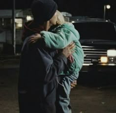 a man and woman hugging in front of a truck at night with their arms around each other