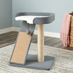 a cat scratching post in the corner of a room with a rug on the floor