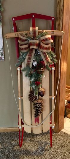 a wooden sled with pine cones and christmas decorations on the top, tied to it