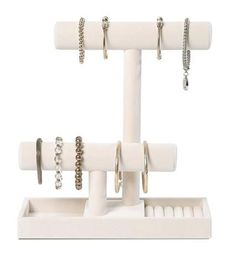 a white jewelry holder with rings and bracelets hanging from it's sides, on a white background