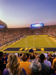 a football stadium filled with lots of people watching the game at sunset or sunrise time