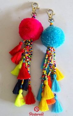 two tasselled pom - pom keychains on a white surface