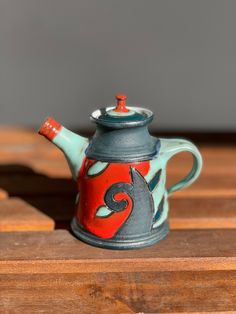 a ceramic teapot sitting on top of a wooden table