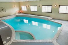 an indoor swimming pool in a large room with windows and tile flooring on the walls