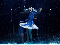 a woman is dancing in the rain on stage