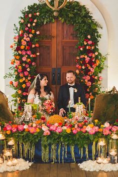 the bride and groom are sitting in front of an elaborate table with flowers on it