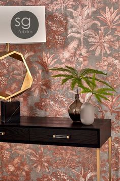 a table with a lamp, vase and plant on it next to a wallpapered wall