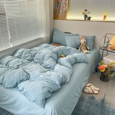 a bed with blue comforters and pillows in a small room next to a window