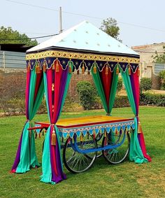 a colorful canopy bed on wheels in the grass