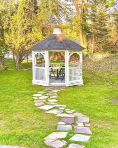 a white gazebo sitting on top of a lush green field